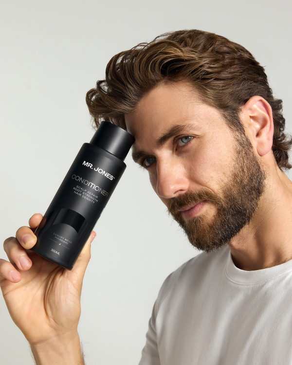 Man holding a black bottle labeled 'MR. JONES' against a neutral background