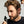 Man applying hair product 'Hair Density Serum' to his hair with a dropper bottle against a neutral background