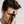Man holding a black dropper bottle labeled 'Mr. Jones Hair Density Serum' close to his face against a plain background