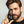 Man holding a bottle of Mr. Jones Beard Serum product against a grey background