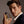 Man holding a perfume bottle labeled 'Valour' against a neutral background
